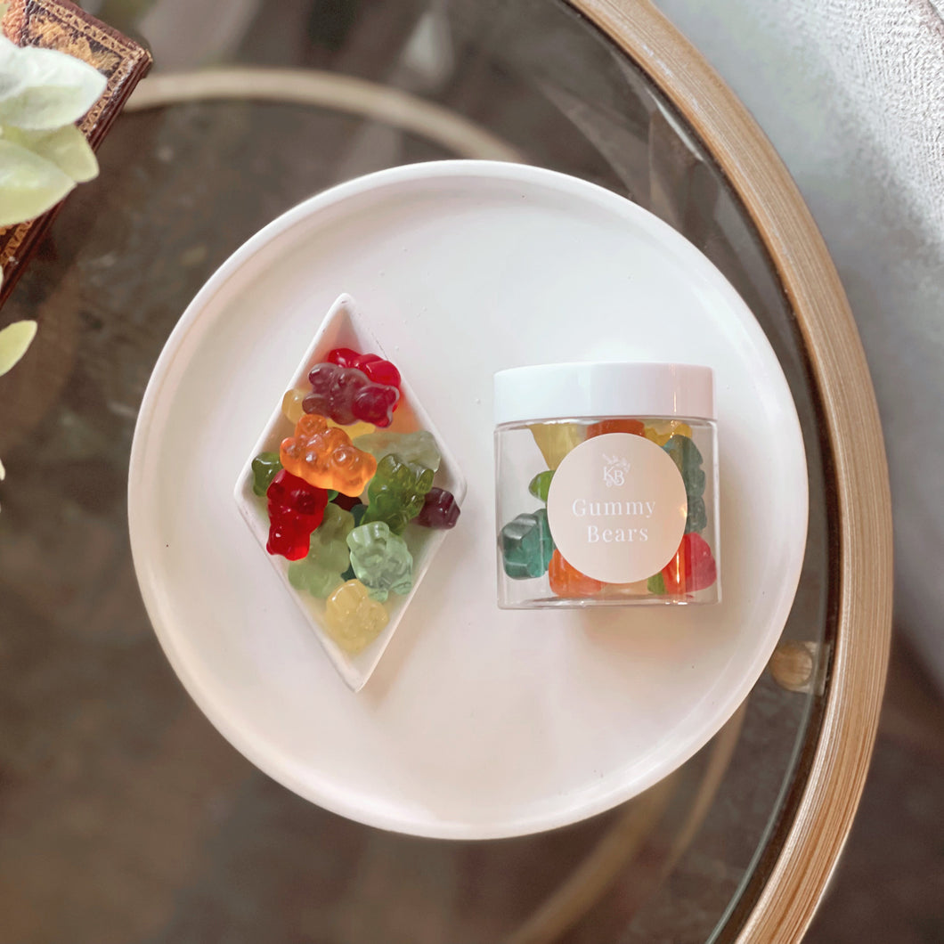 Colorful gummy bear-shaped candies on a white plate with a blurred background